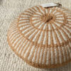 Camel and Natural White round cushion with woven stripes, styled on a light wool rug.