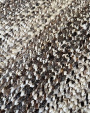 Extreme close-up of the Pepper rug's undyed wool fibers, dark and light strands twisted together
