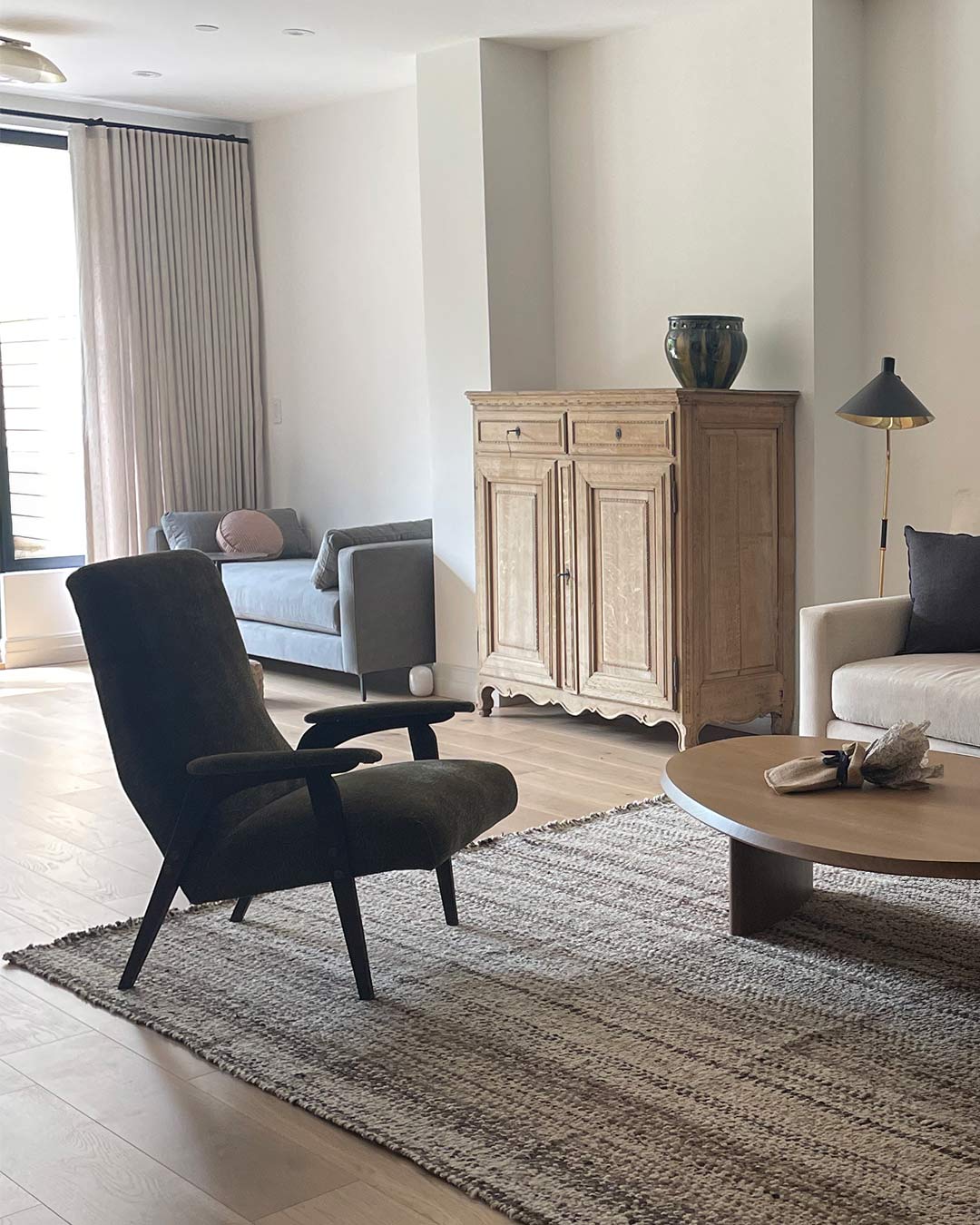 Alfombra lana jaspeada natural Pimienta ambientada en un living con sillón verde oscuro y aparador de madera