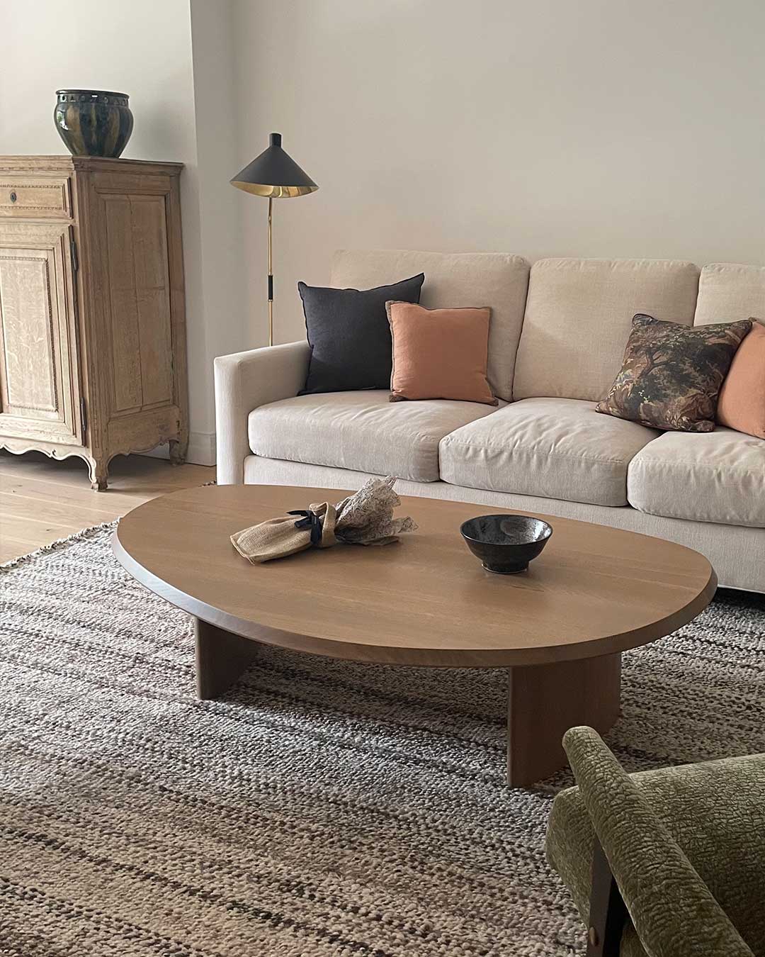 Speckled wool area rug in Pepper under an oval wood coffee table in a warm neutral living room