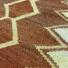 Close-up detail of a handwoven Qom textile with a traditional geometric design featuring different shapes and colors.