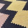 Close-up detail of a handwoven Qom textile with a traditional geometric design featuring different shapes and colors.