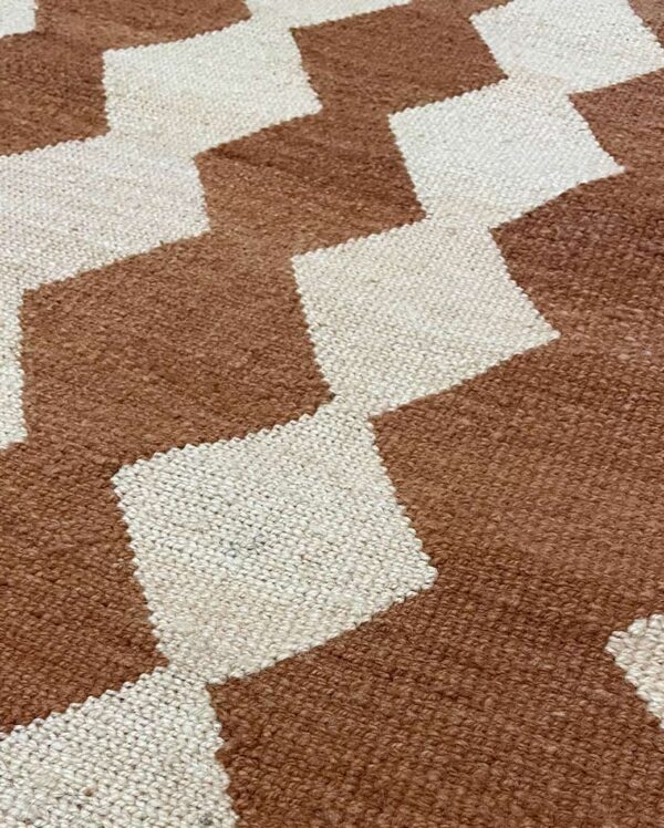 Detalle de cerca de un textil Qom tejido a mano con un diseño geométrico tradicional que presenta diferentes formas y colores.