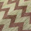 Detalle de cerca de un textil Qom tejido a mano con un diseño geométrico tradicional que presenta diferentes formas y colores.