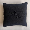 Black square wool cushion, shown from the back with woolen tie closure.