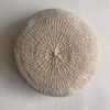 Beige-colored round cushion made of handwoven wool, shown from the front.