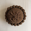 Chocolate Brown-colored round cushion with handmade pom poms, shown from the back.
