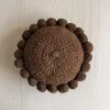 Chocolate Brown-colored round cushion with handmade pom poms, shown from the front.