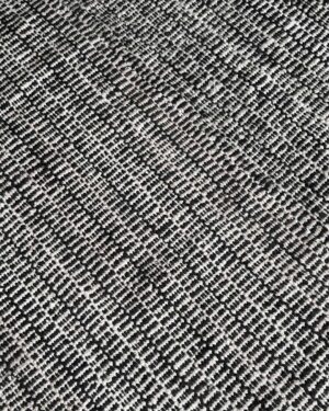 Close-up of black and natural woven wool rug showing bold comb-like pattern and handwoven texture.