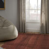 Burgundy wool rug in a living space with natural light, a bean bag, and soft neutral curtains.