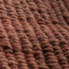 Close-up of the burgundy wool rug showing the handwoven texture and rich natural fibers.