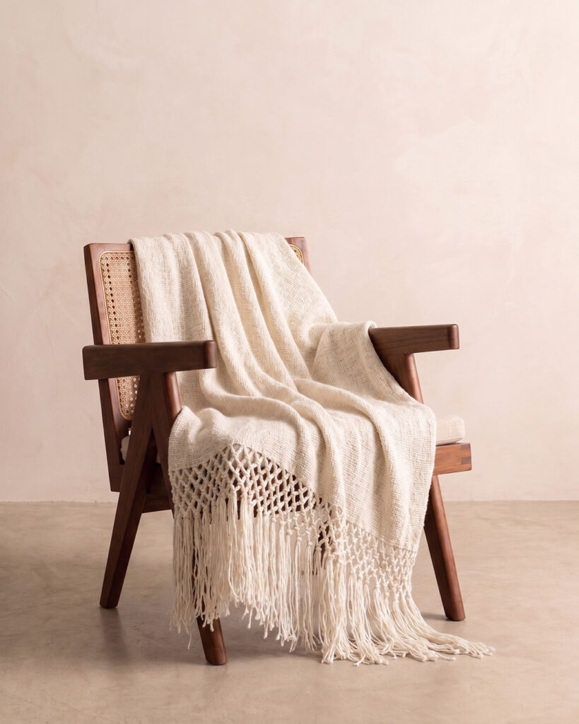 Natural White llama throw draped over a cane and wood armchair with knotted fringe