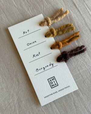 Yarn sample card with four natural wool colors by ANDINA: Nut, Onion, Rust, and Burgundy.