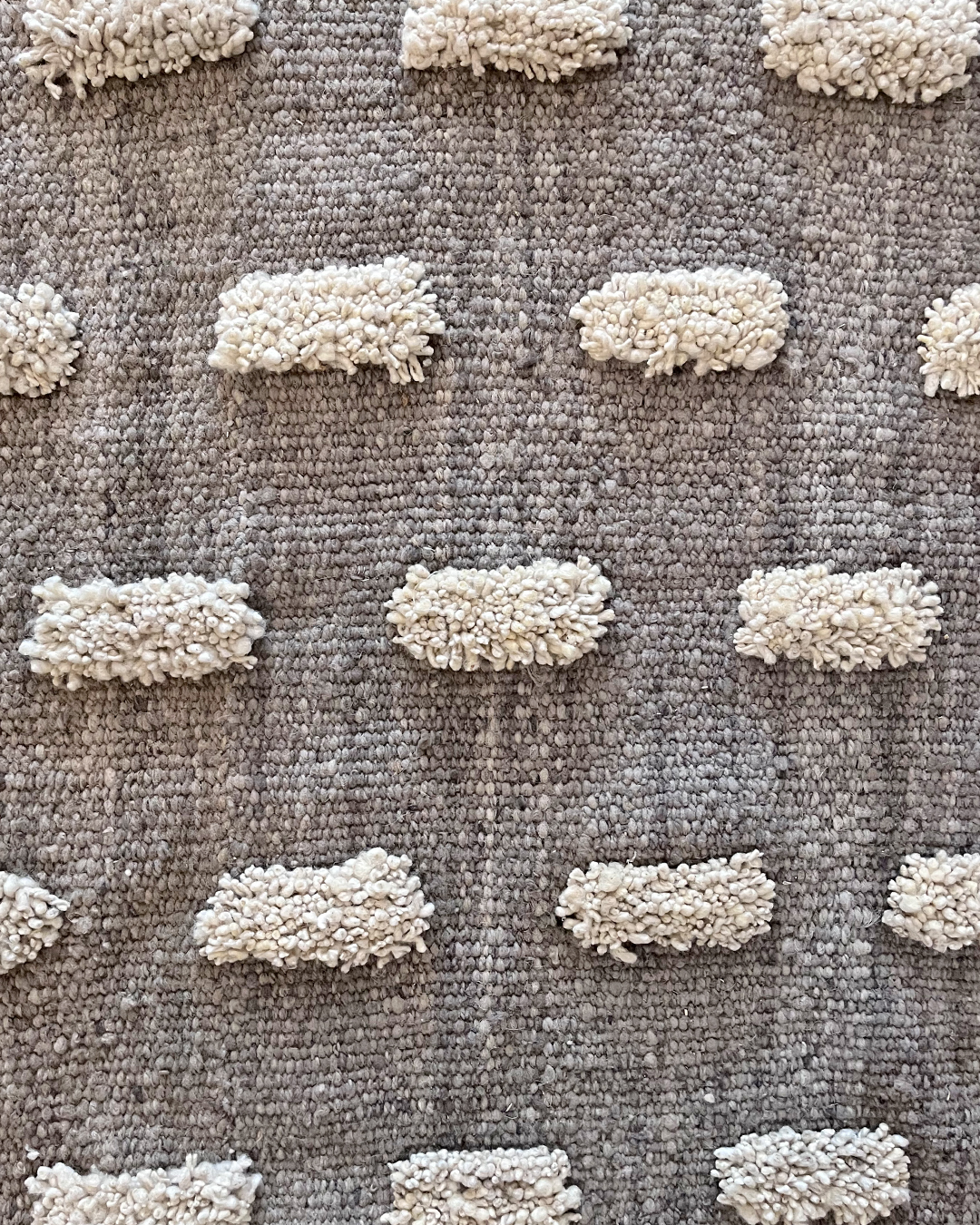 Textura en primer plano de pompones sobre alfombra gris.