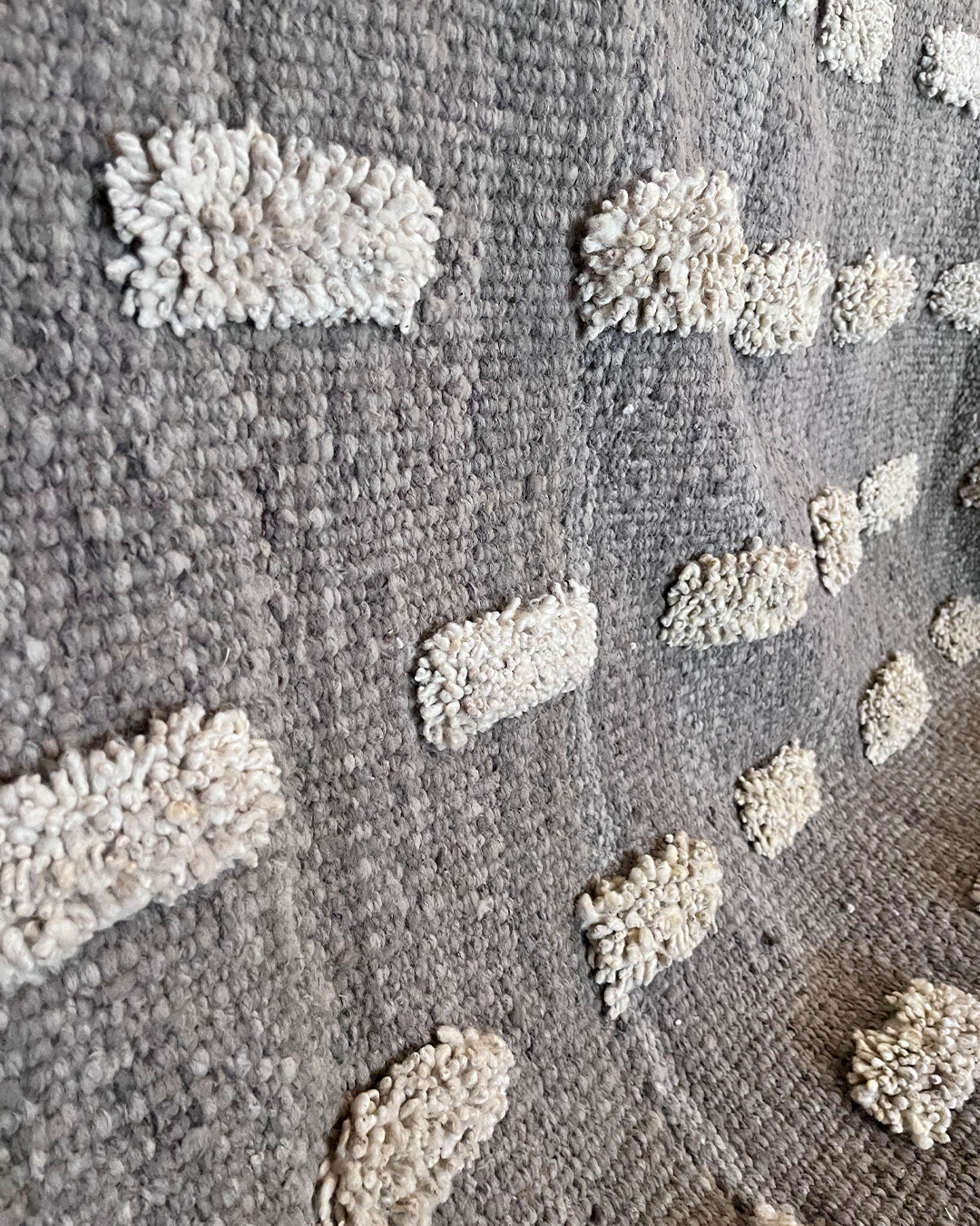 Vista en detalle de los pompones sobre fondo de lana gris humo.