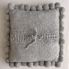 Gray-colored square cushion with handmade pom poms, shown from the back.