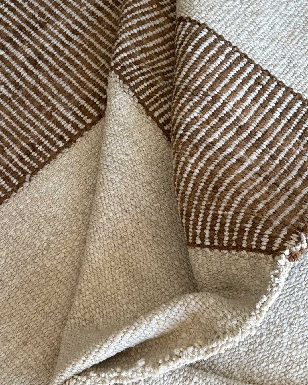 Detalle de alfombra natural y nuez con patrón Escalera y tejido artesanal visible