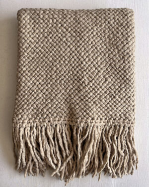 Beige handwoven wool throw with fringes, neatly folded to show texture and weave.