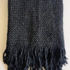 Folded black wool throw with fringes, presented front-facing on a light background.