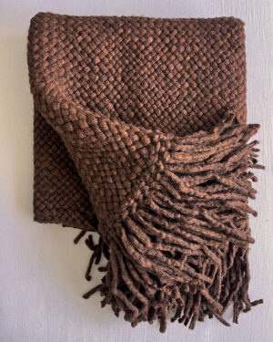 Folded chocolate brown handwoven wool throw with fringes, displaying the texture of the wool and tight weave.