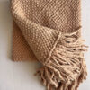 Camel wool throw partially unfolded with visible fringes and woven pattern.