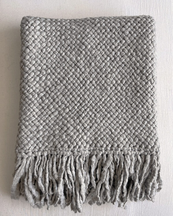 Gray handwoven wool throw with fringes, neatly folded to show texture and weave.