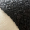 Close-up of the wool weave texture in black, highlighting individual fibers.