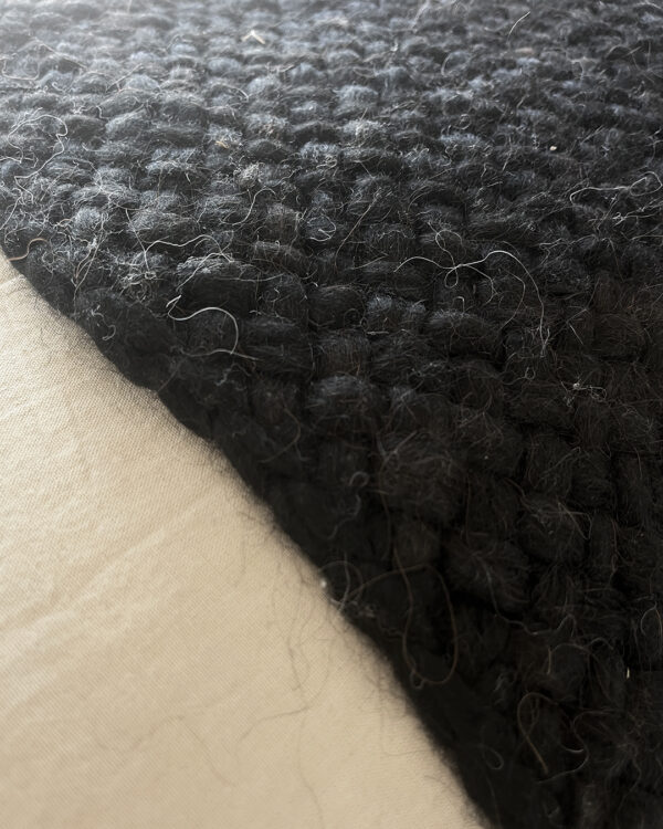 Handwoven black wool throw made from natural sheep's wool, with a close-up of its thick, textured weave.