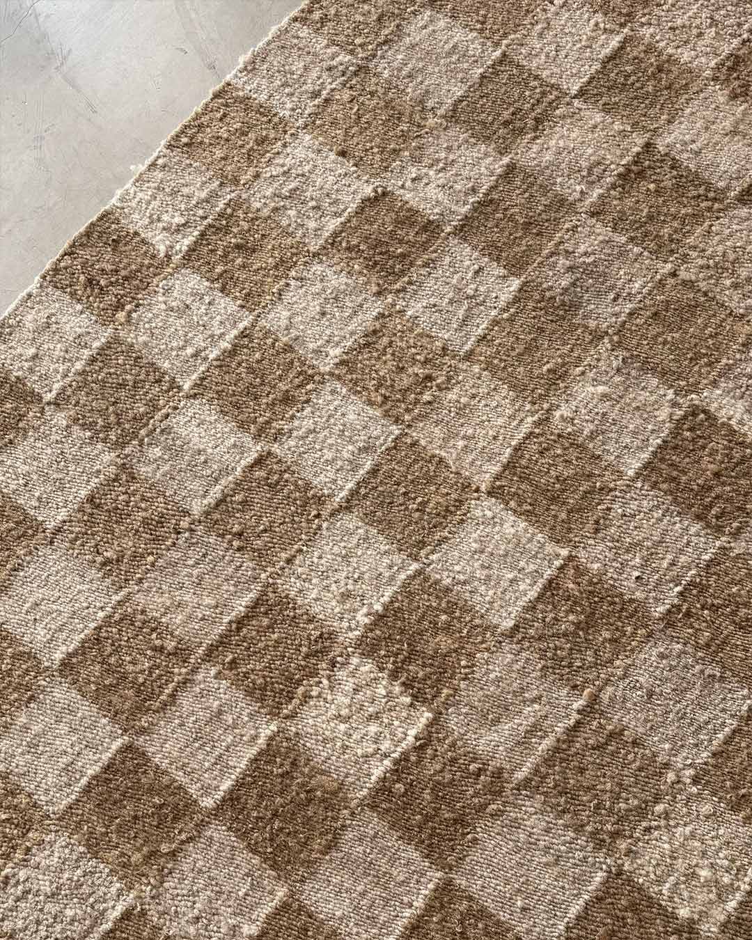 Top view of wood and sand checkered wool area rug