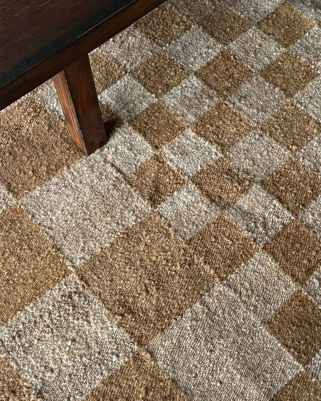 Wood and sand checkered rug styled under wooden table