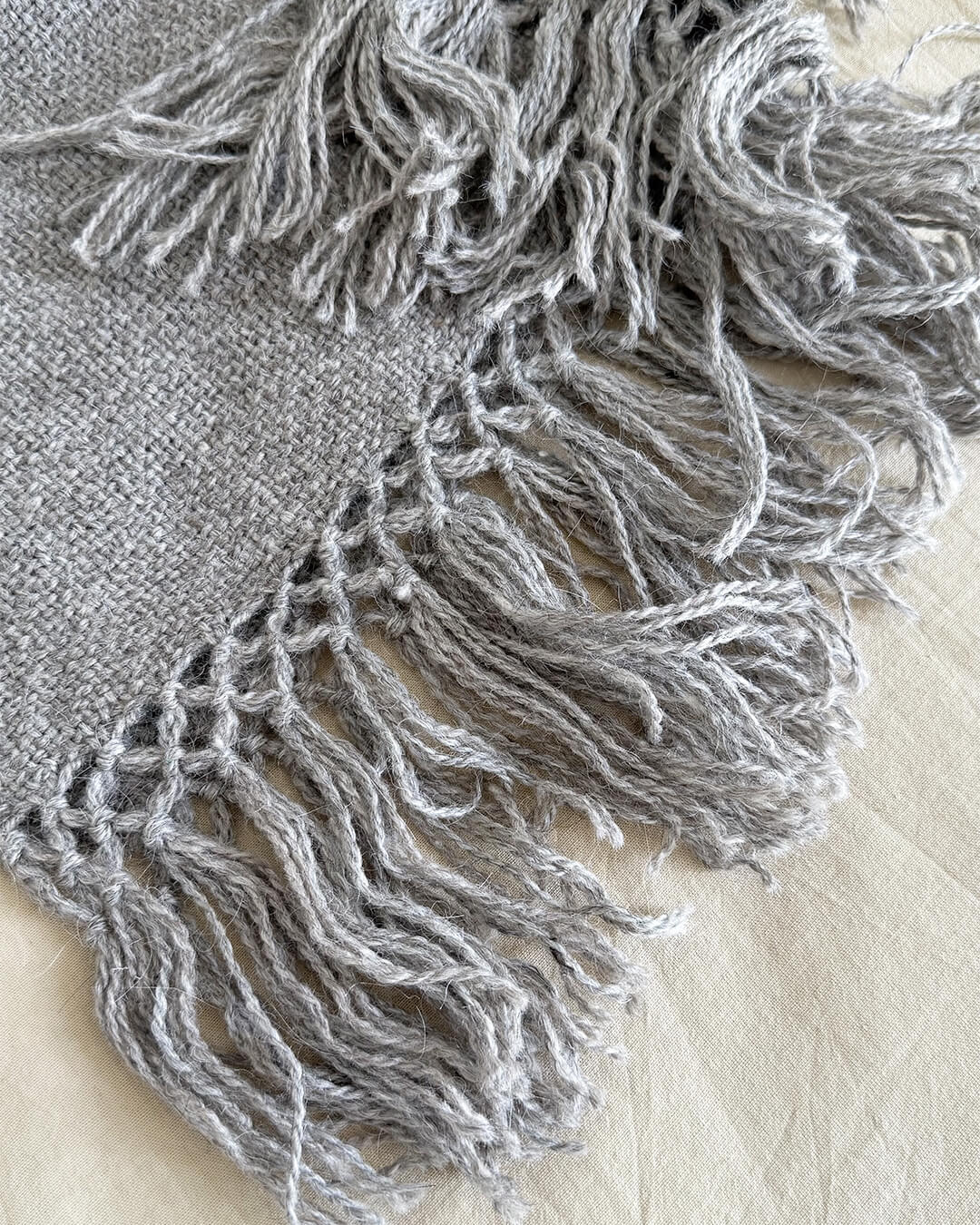 Close-up of ANDINA’s Ash llama throw with soft fringes and handwoven texture.