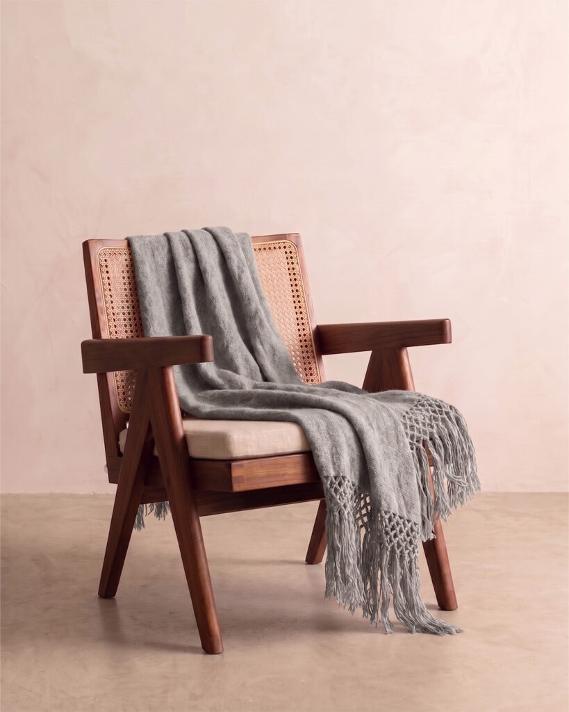 Ash llama throw draped over a cane and wood armchair with knotted fringe