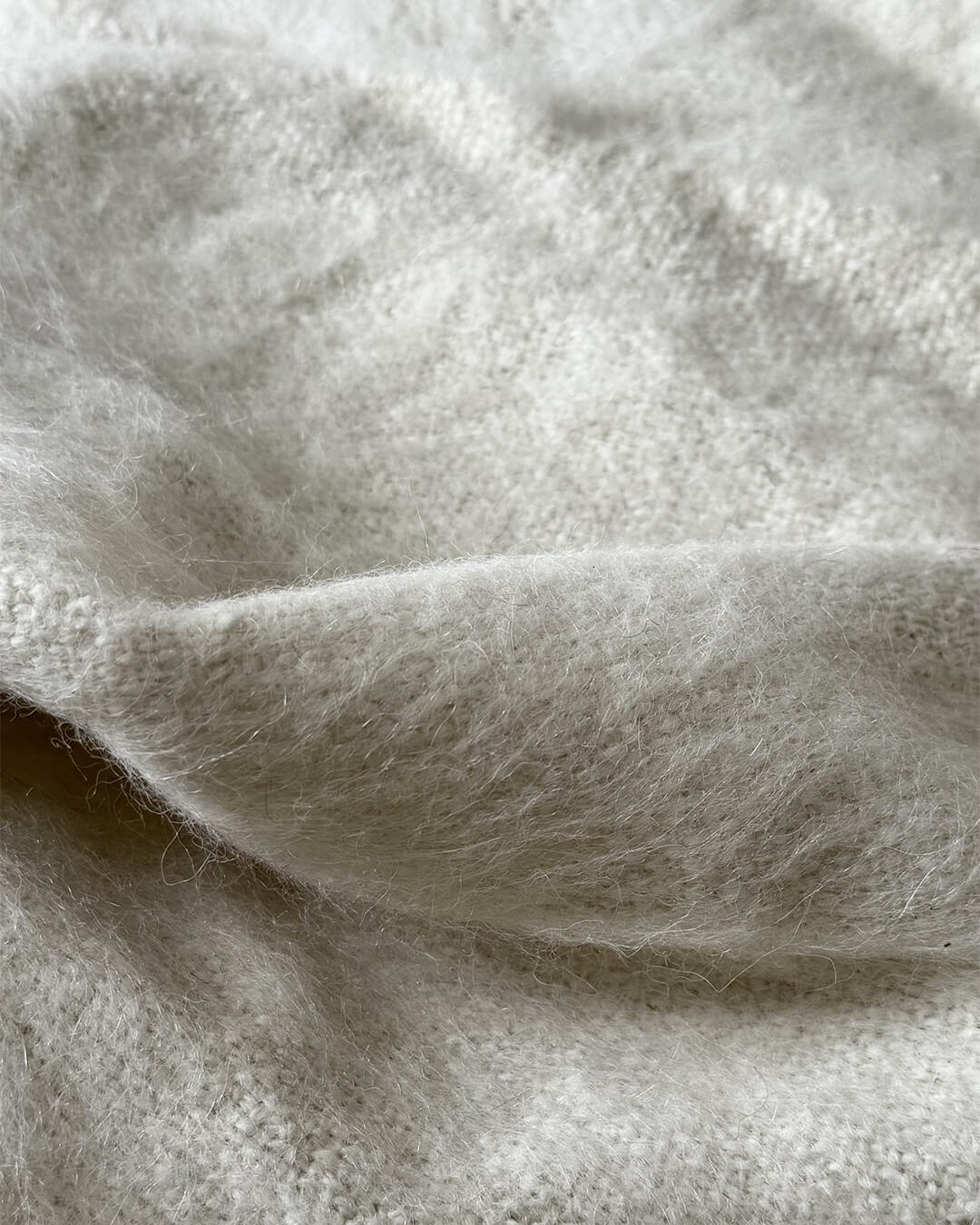 Soft brushed llama throw in Natural White by ANDINA, showing fine fiber details under natural light.