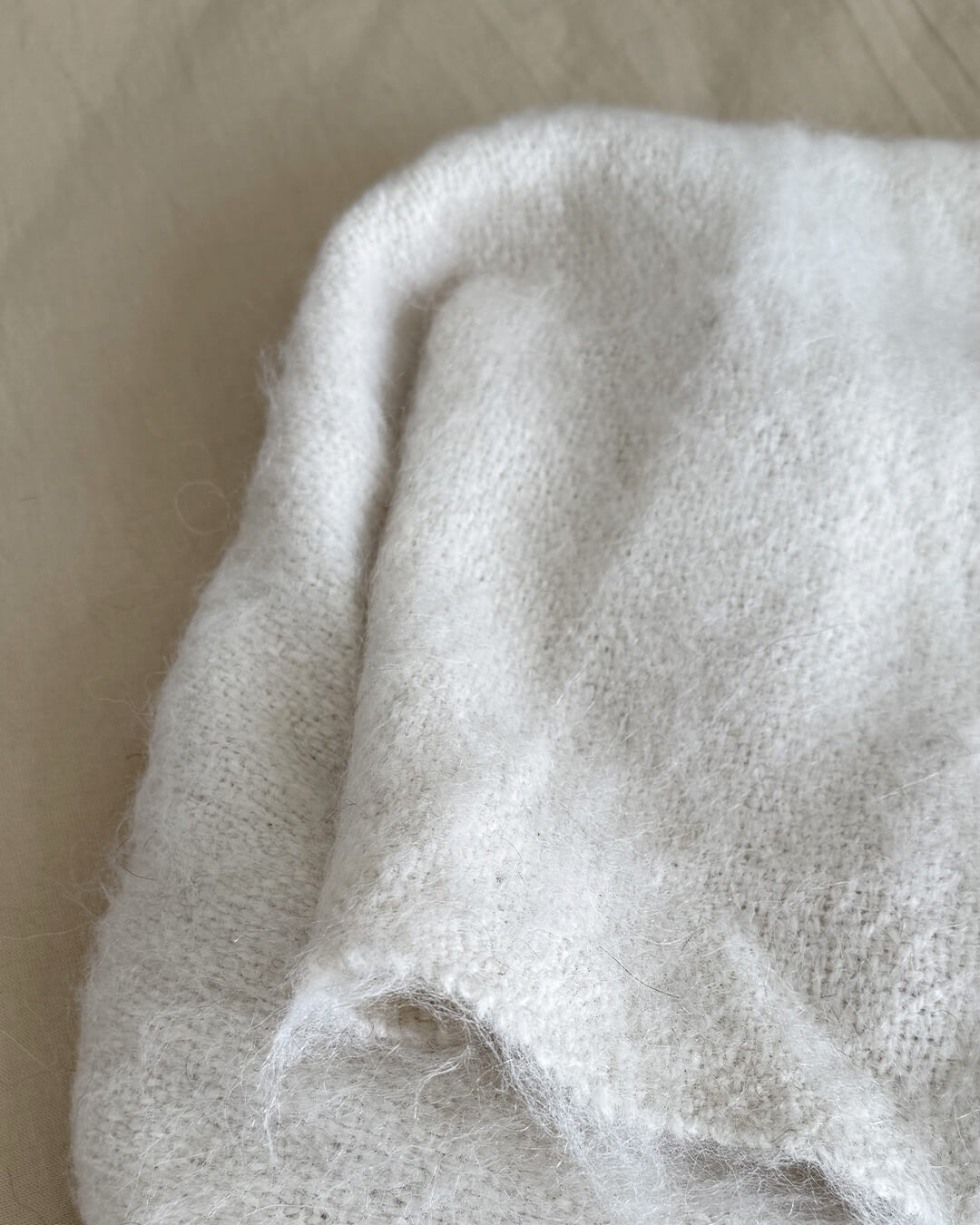 Close-up of ANDINA’s Natural White brushed llama throw showing its soft and airy fiber texture.