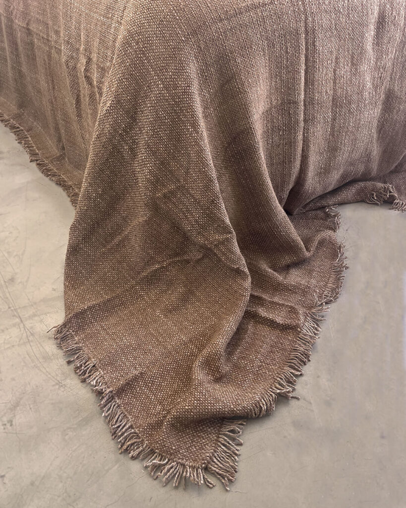 Handwoven llama bed quilt camel tone on minimalist bed with soft natural light