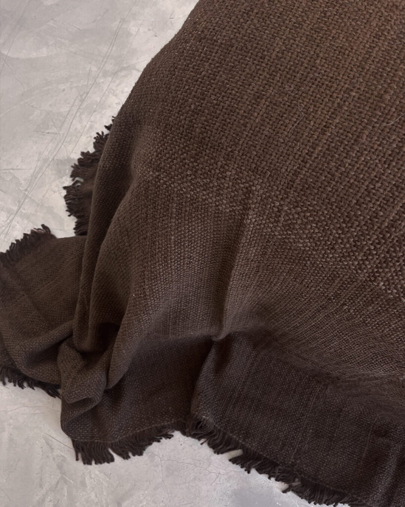 Undyed llama bed quilt chocolate brown with handwoven fringe resting close to floor