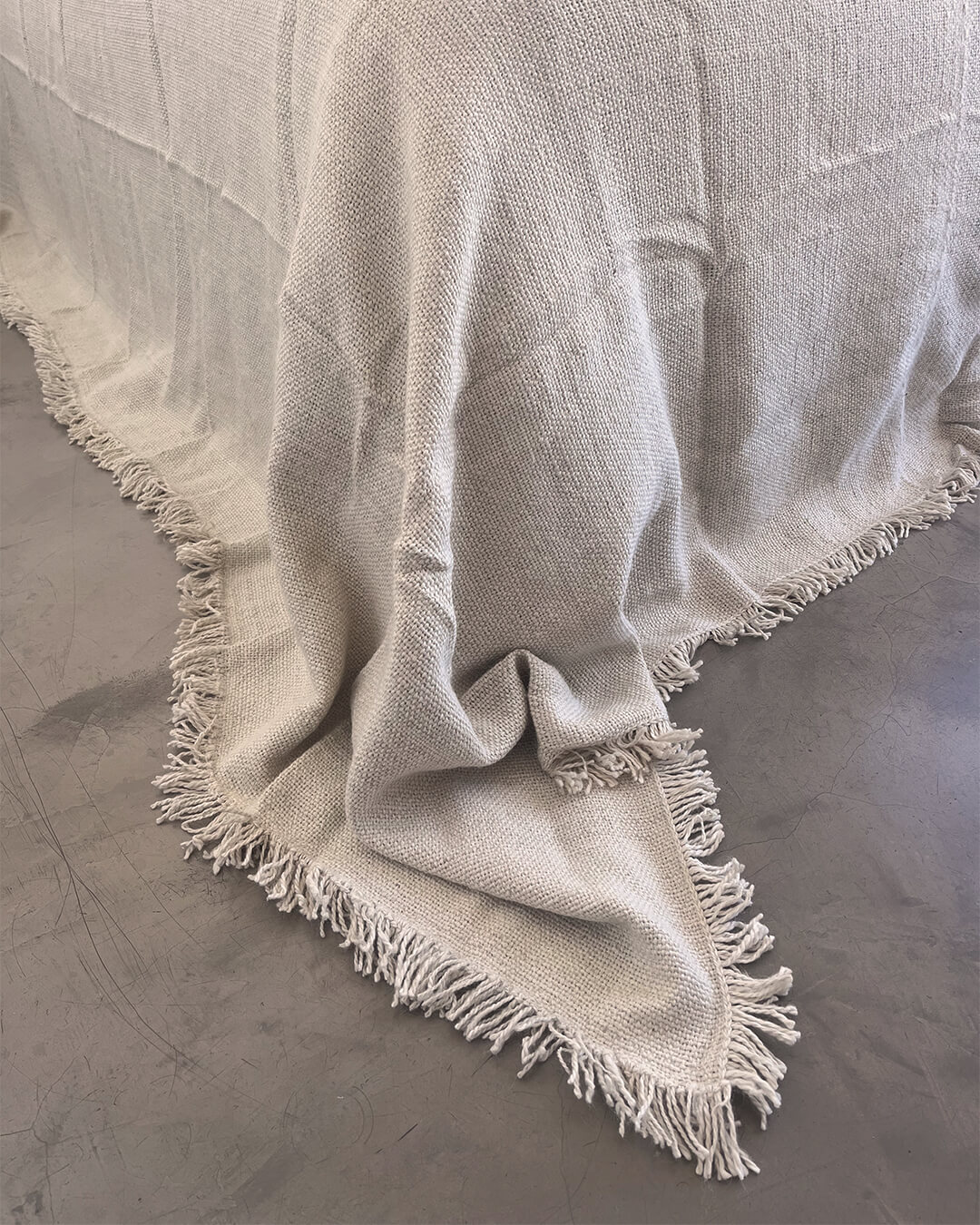 Frasada blanco natural de llama caída suavemente con flecos y tejido artesanal visible.
