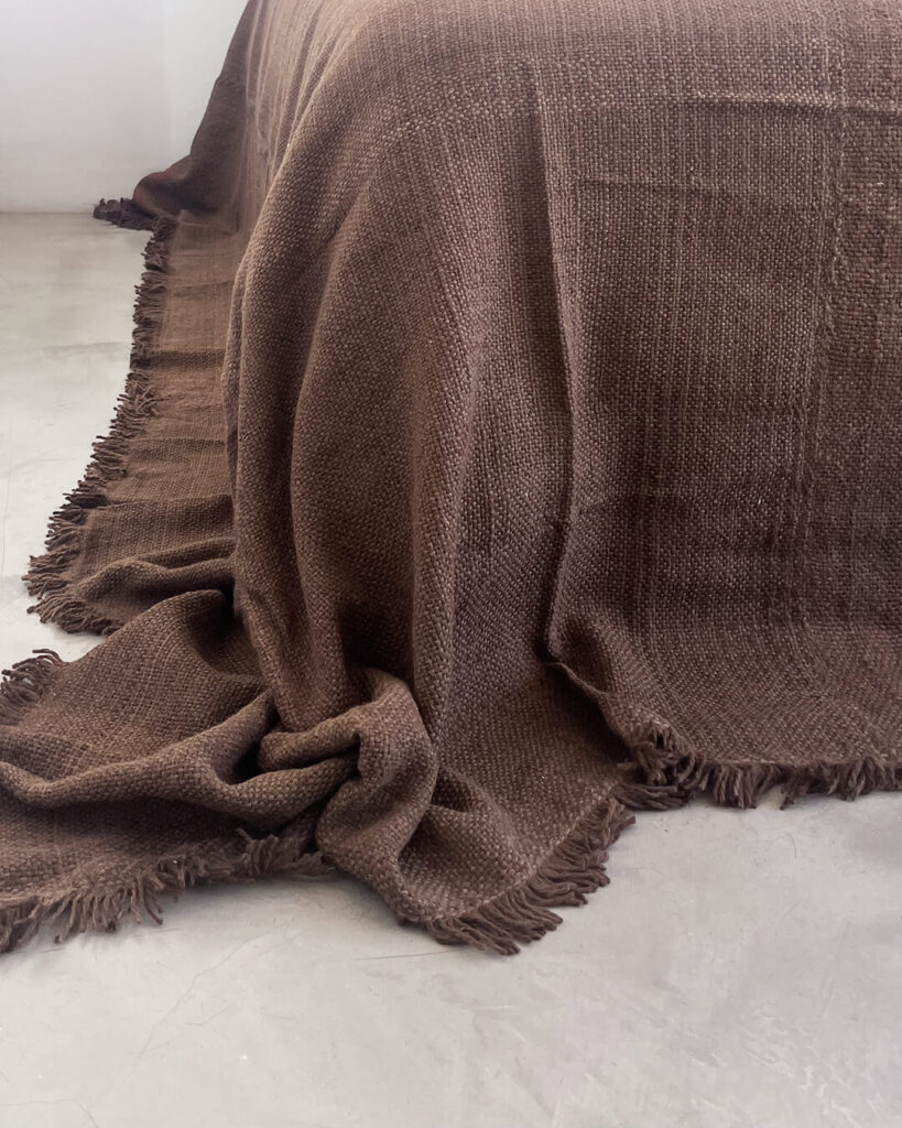 Llama bed quilt oak brown draped over bed showing handwoven fringe and warm brown tone