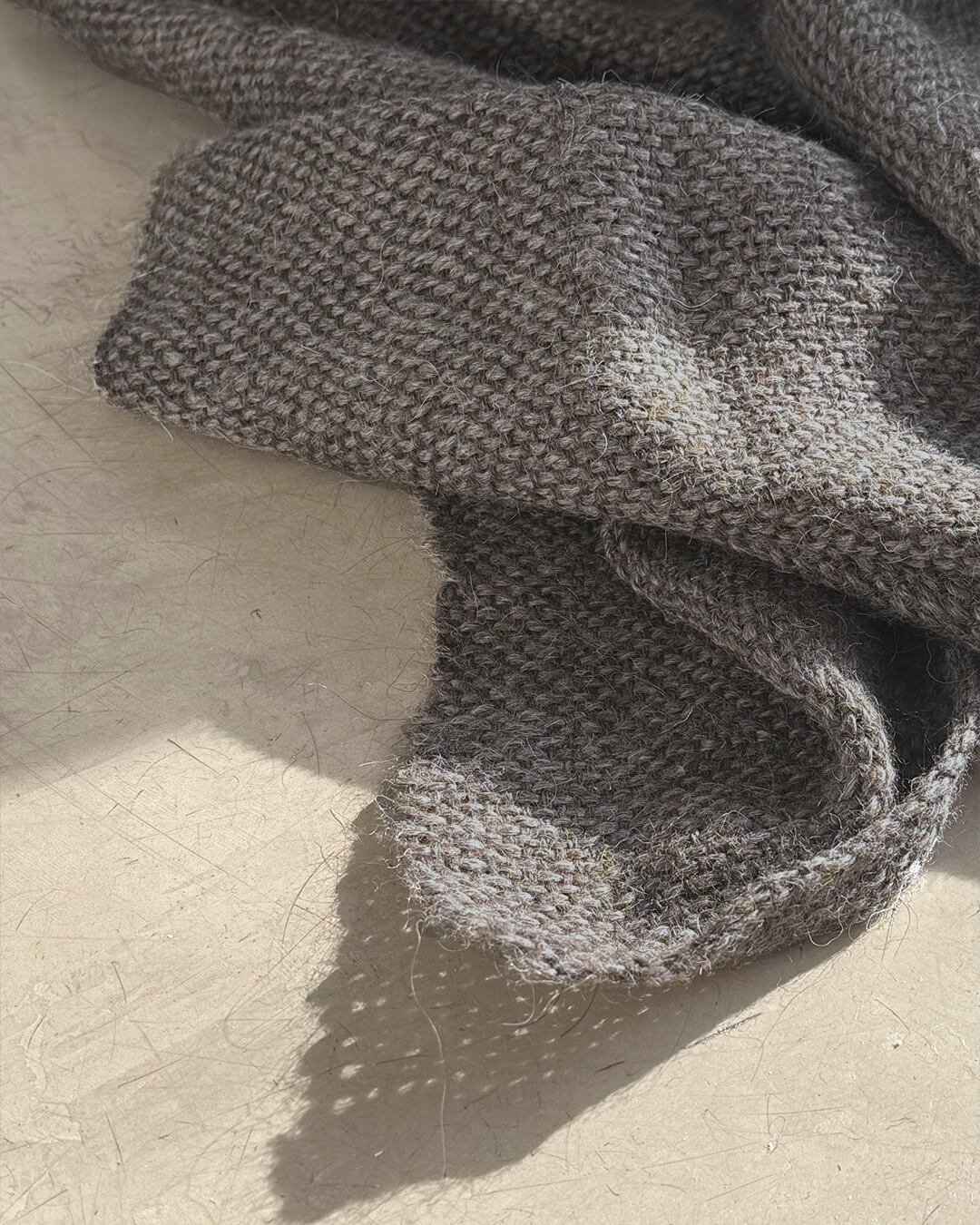 Primer plano de la frazada de llama sin teñir de ANDINA en tono Sombra Gris, mostrando su textura suave y acabado artesanal.