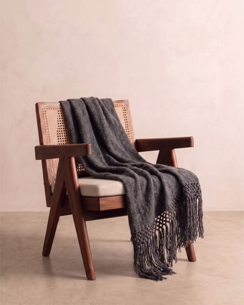 Shadow llama throw draped over a cane and wood armchair with knotted fringe