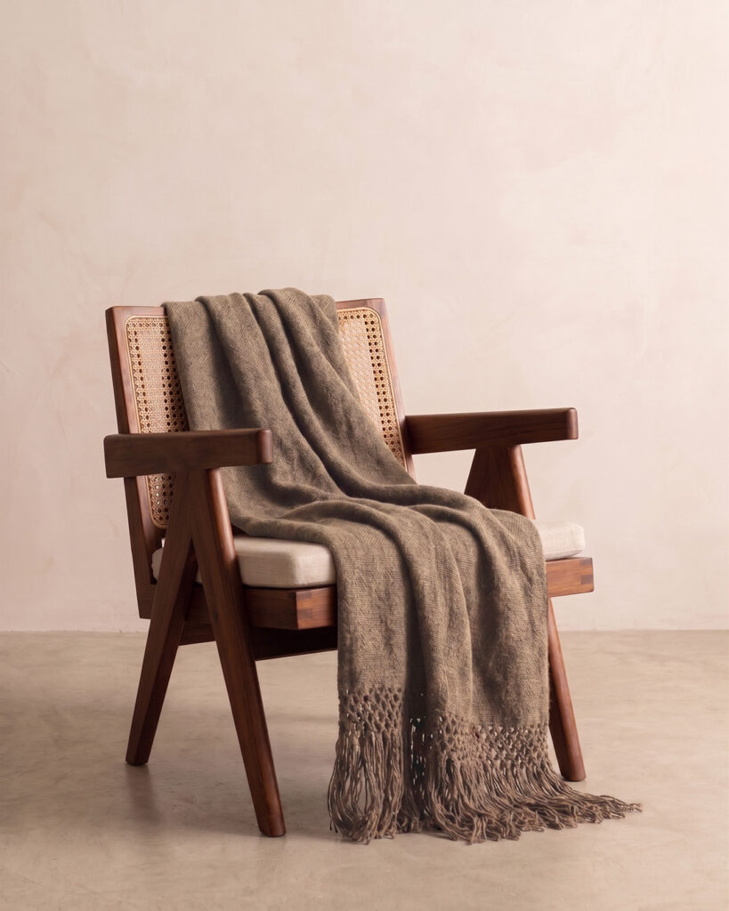 Camel llama throw draped over a cane and wood armchair with crochet fringe