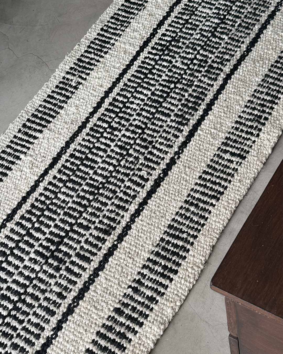Full length view of the Quebracho runner rug in natural and black wool.