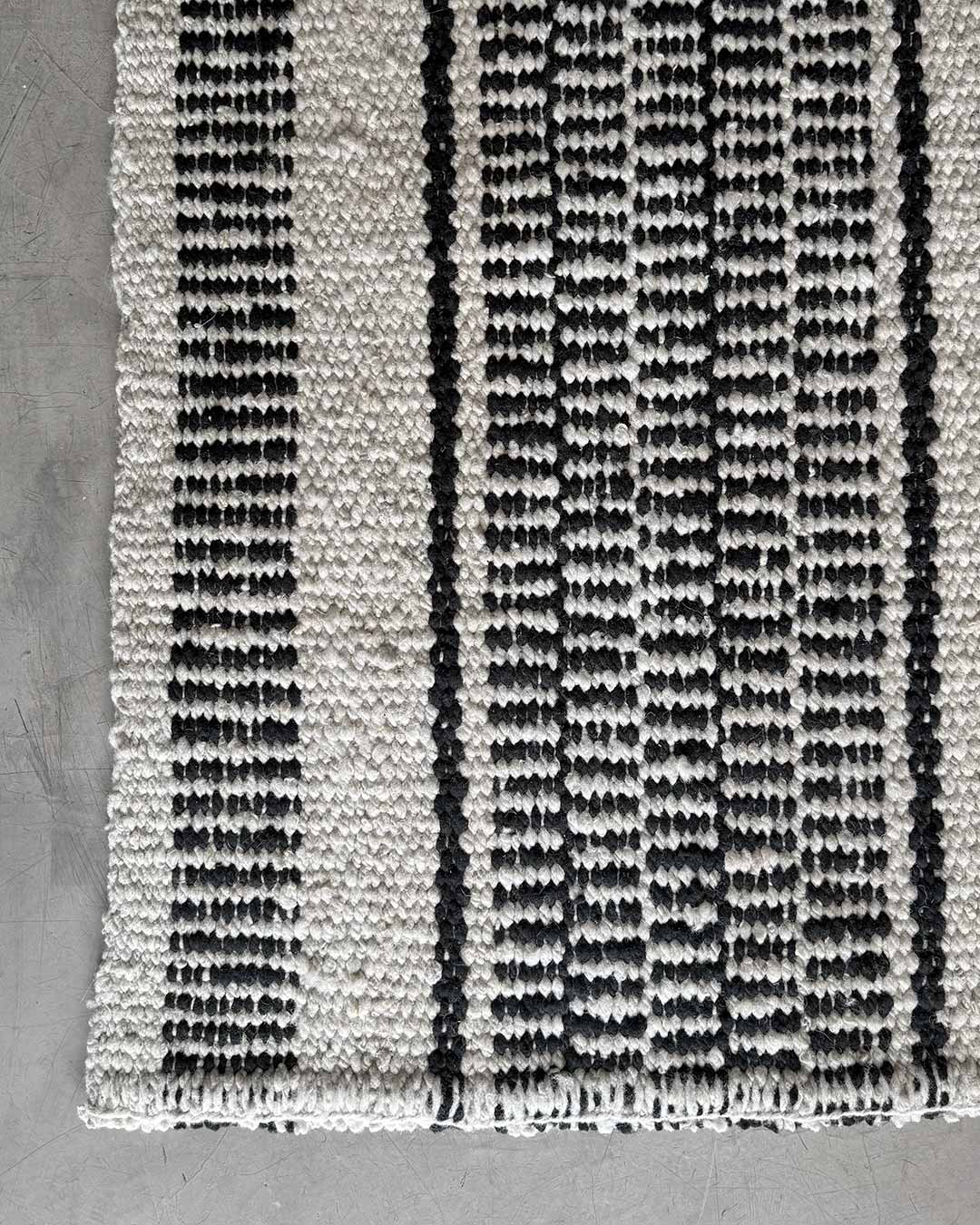 Top view of the Quebracho runner rug end in natural and black wool.