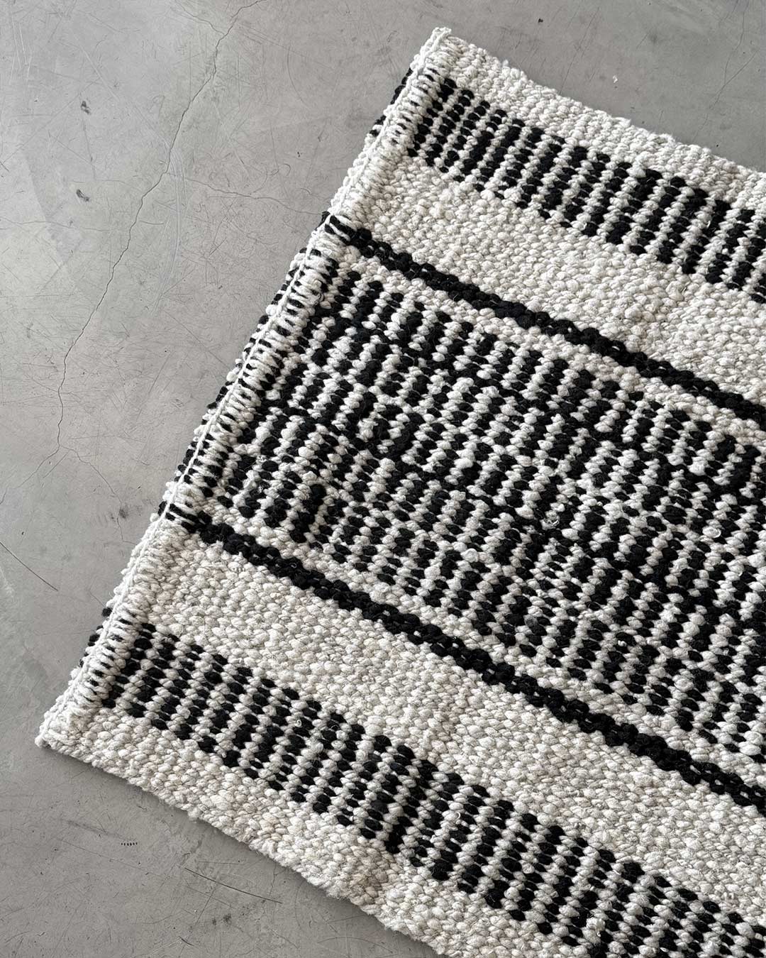 Corner detail of the Quebracho runner rug in natural and black handwoven wool.