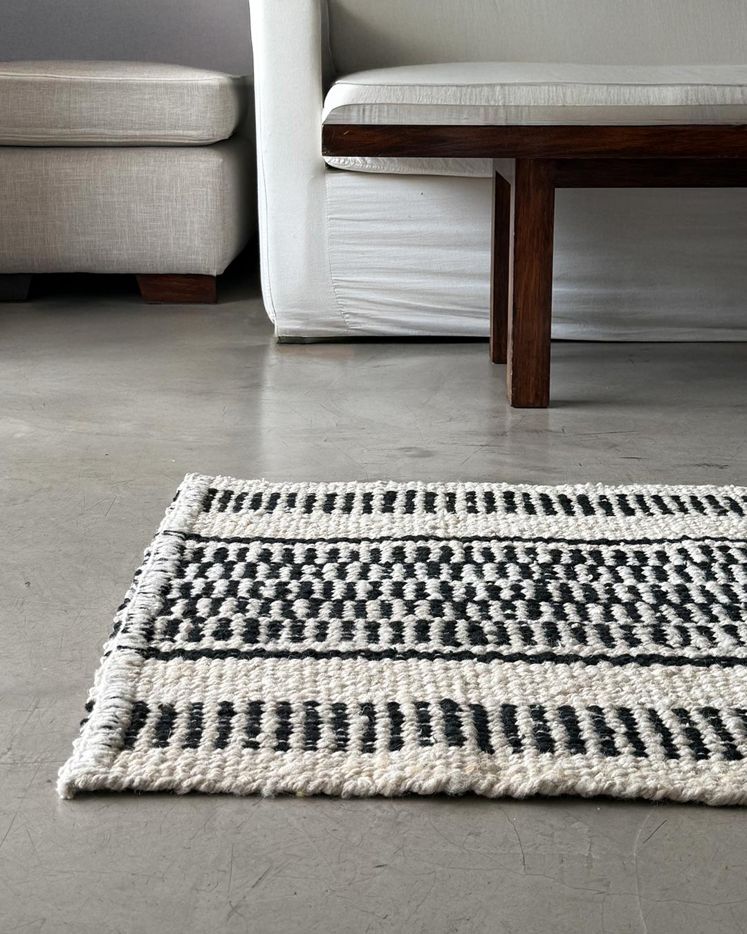 Quebracho runner rug in natural and black wool placed in a minimalist living space.
