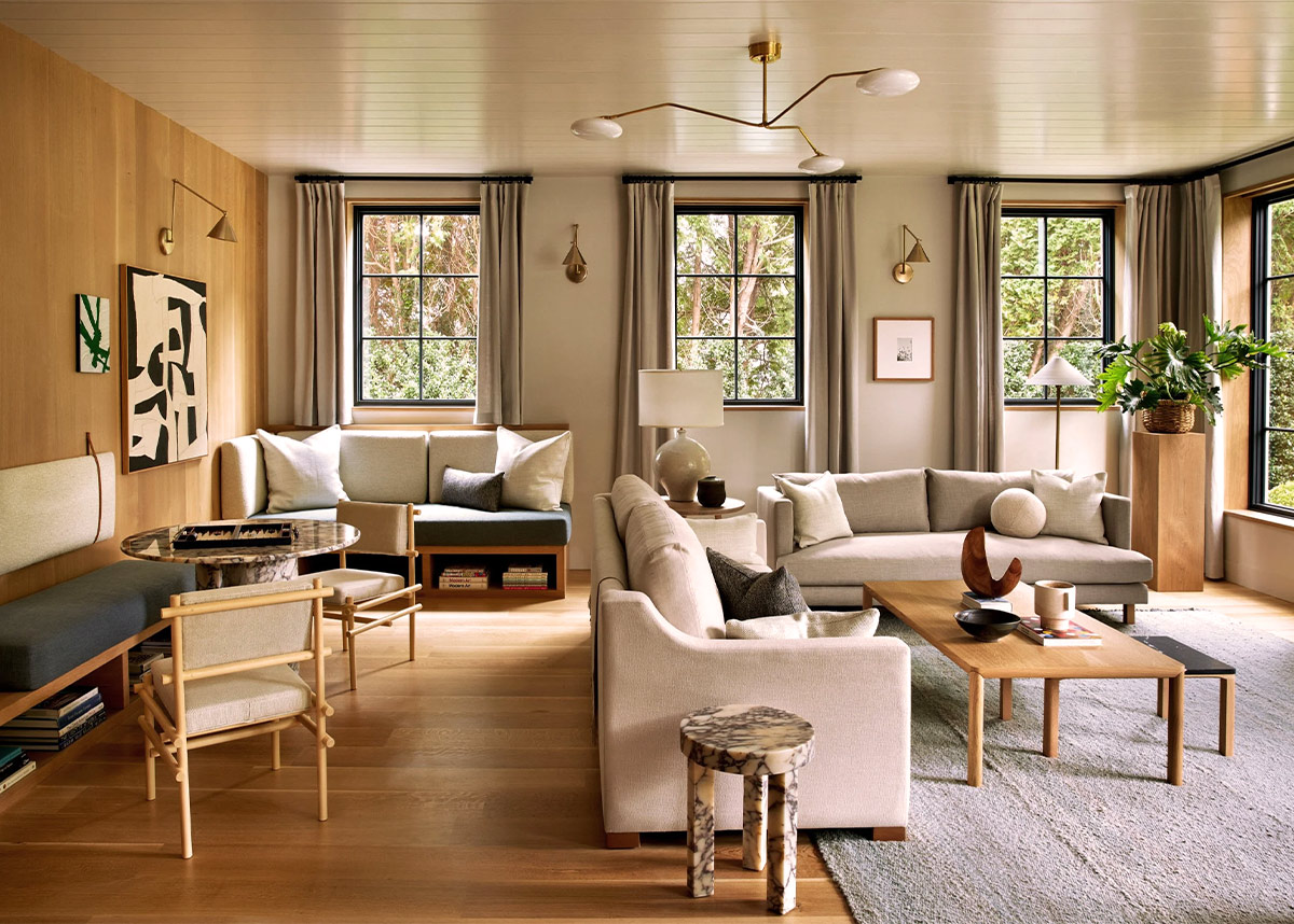 Modern living room with neutral wool area rug, beige sofas, oak coffee table and black-framed windows