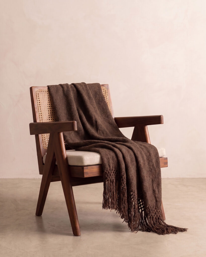 Chocolate llama throw draped over a cane and wood armchair with knotted fringe