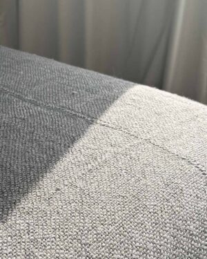 Ash llama bed quilt draped over bed corner showing handwoven texture and short fringe detail