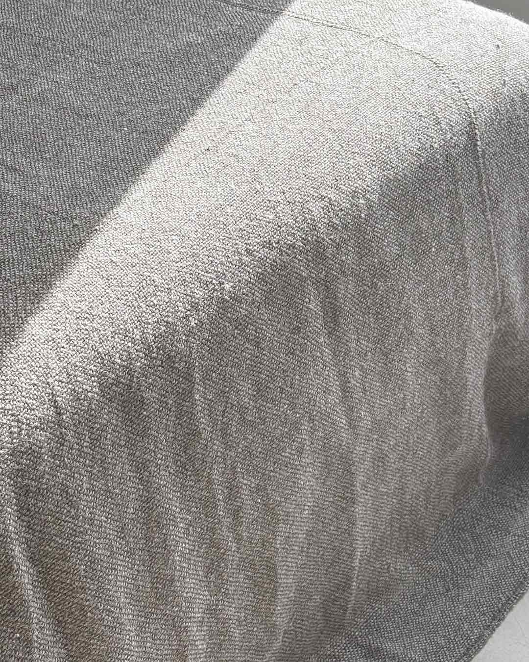 Full view of ash llama bed quilt on concrete floor — light gray undyed llama fiber with short fringe