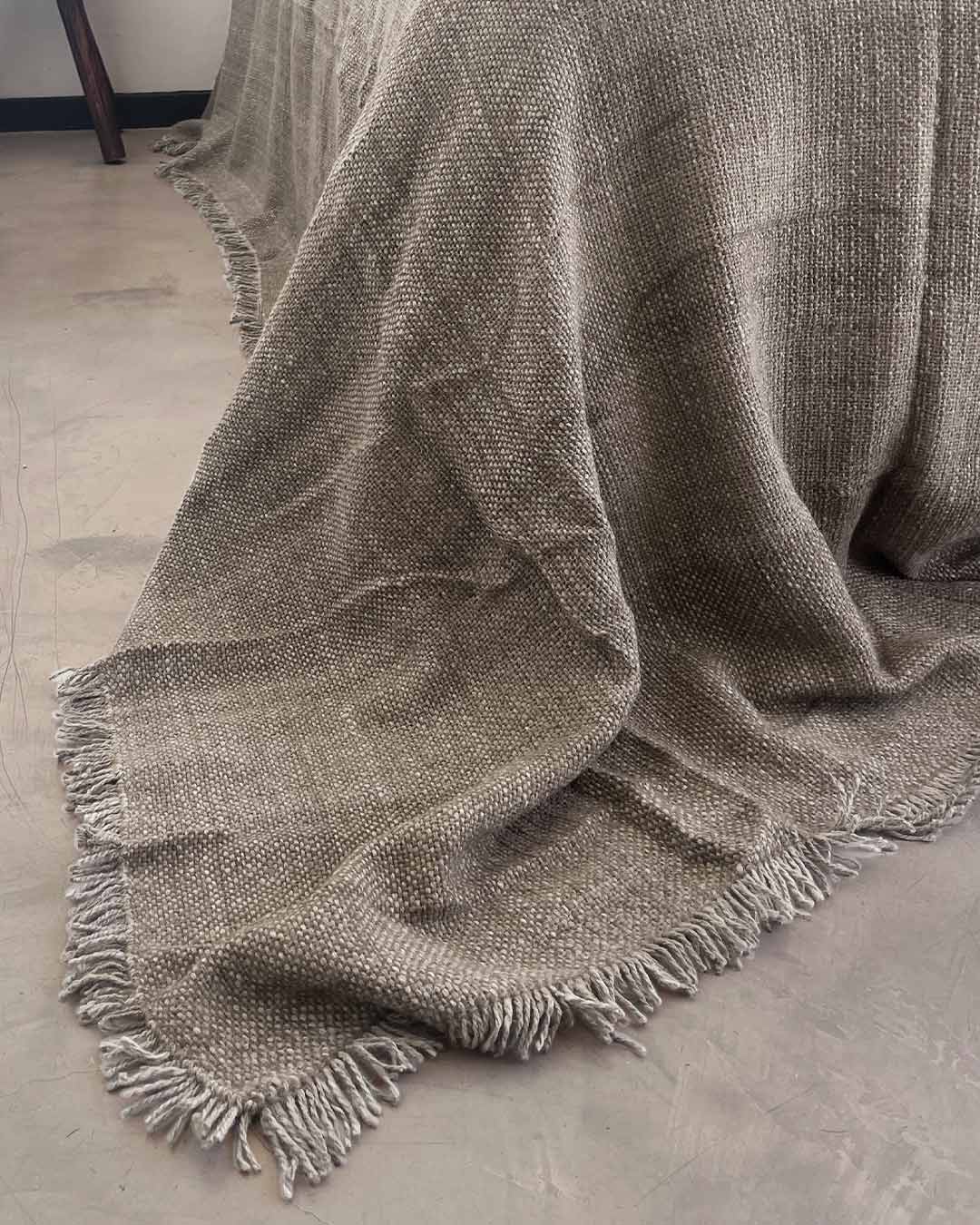 Close-up of oat llama fiber texture showing soft pale beige weave of undyed handwoven bed quilt
